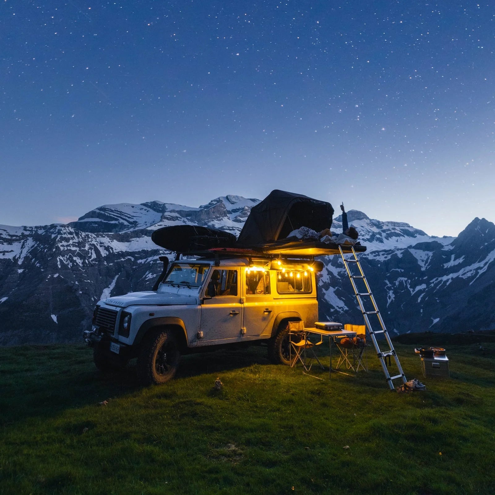 Un couple installé dans une tente de toit 2 places Roof Space 2. Le mode panoramique leur permet d'observer les étoiles en étant allongé.